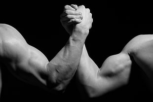 grayscale photo of two man holding hands